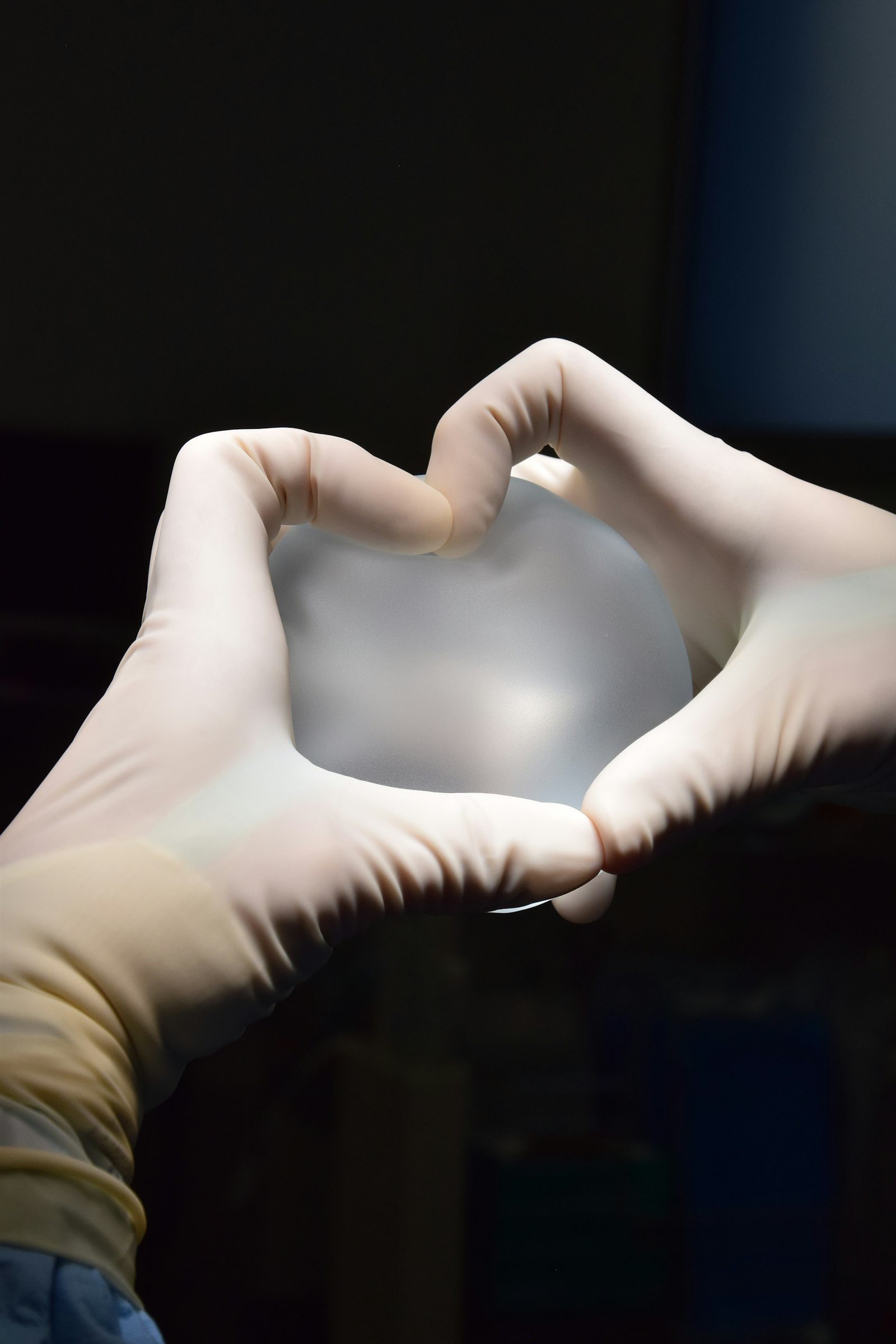 Des mains gantées tenant un implant mammaire en silicone